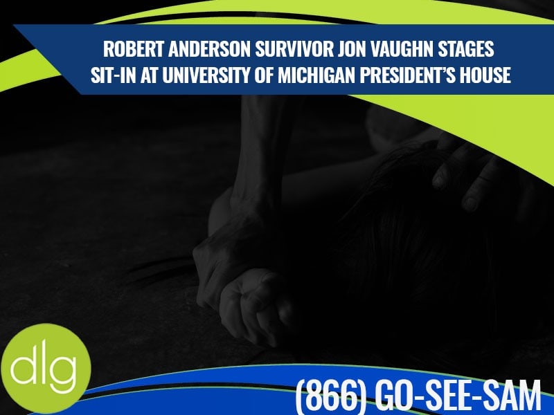 A person’s hand pins another person’s arm to the ground. Overlaid text discusses Jon Vaughn’s sit-in protest at the University of Michigan president’s house.