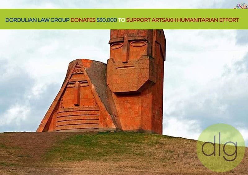 Two large stone sculptures on a grassy hill with a banner stating “Dordulian Law Group donates $30,000 to support Artsakh humanitarian effort.”.