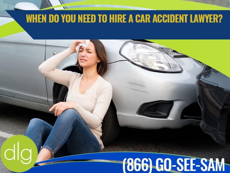 A woman sits on the ground beside a damaged car, holding her head, with a banner asking when to hire a car accident lawyer and a phone number displayed.
