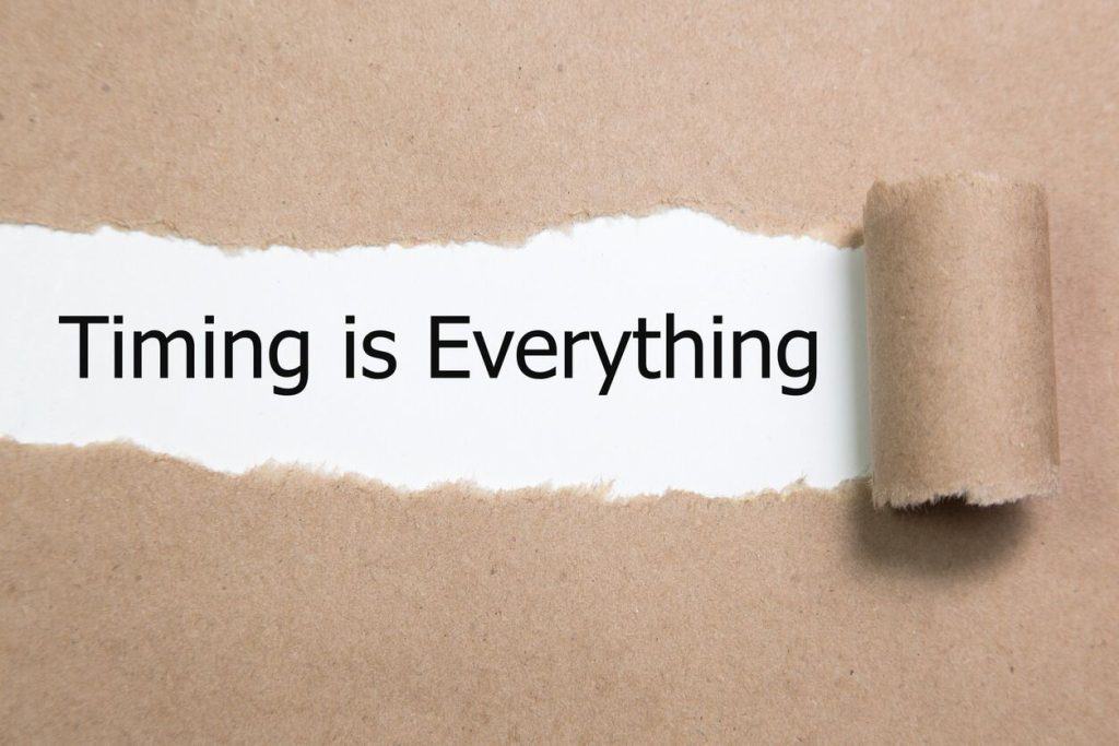 A piece of brown paper is torn open to reveal the words "Timing is Everything" printed underneath.