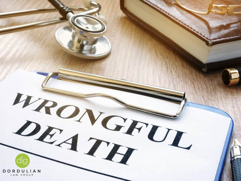 A clipboard with a document labeled "WRONGFUL DEATH," a stethoscope, a book, and a pen are on a desk.